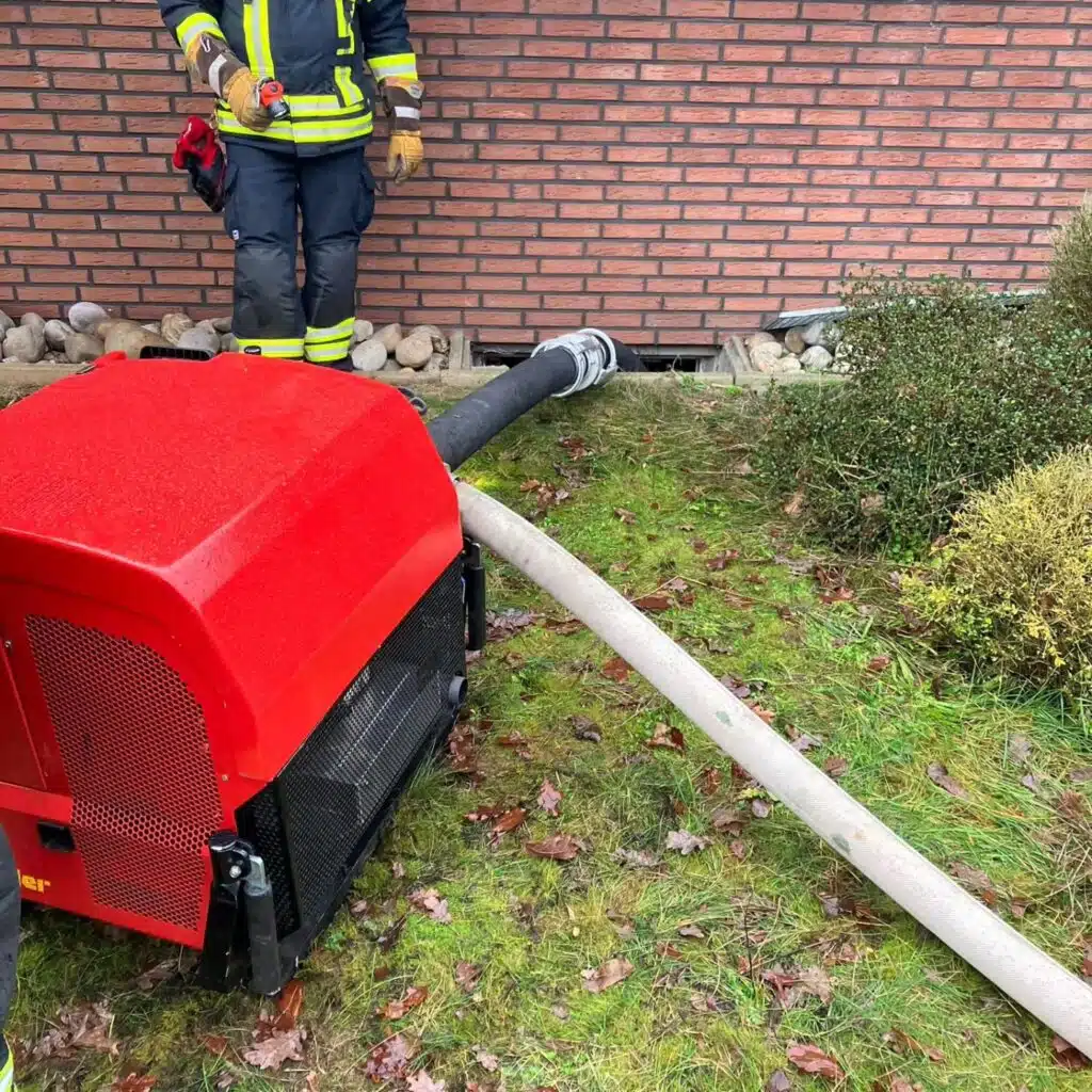 Feuerwehr mit Tragkraftspritze vor Gebäude