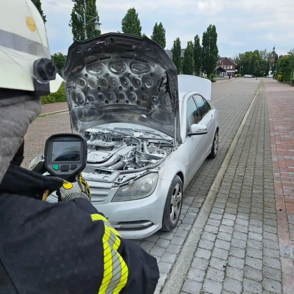 Feuerwehr mit Wärmebildkamera an Motorraum von PKW