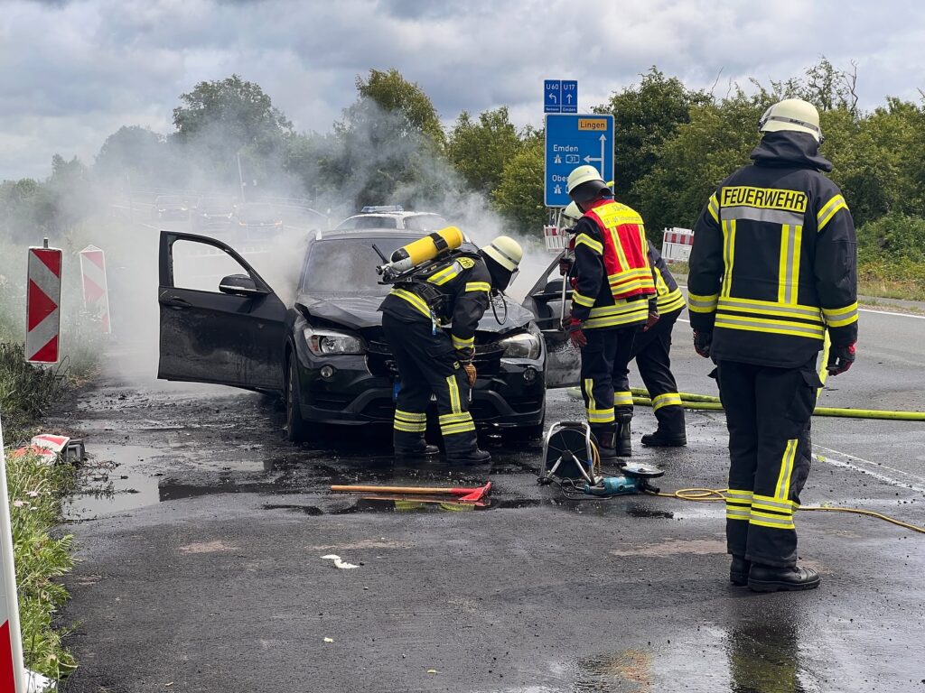 Feuerwehrleute beim ablöschen des brennenden Fahrzeugs.